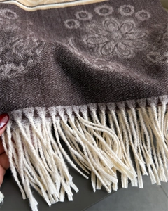 Detail of dark brown floral jacquard knit scarf featuring long cream-colored fringes