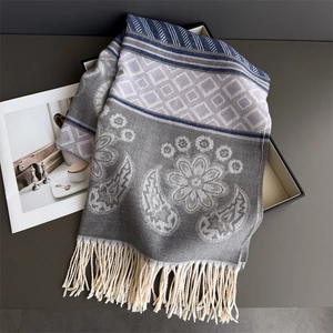 Close-up of floral cashmere feel scarf with paisley patterns and tassels in a gift box