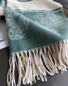 Close-up of soft green floral knit scarf showing intricate texture and long white tassels