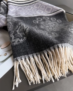 Close-up of floral jacquard knit scarf showing soft cashmere texture and long fringe detail
