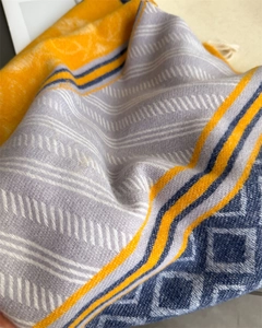 Close-up of jacquard scarf fabric with geometric patterns and soft white fringe tassels