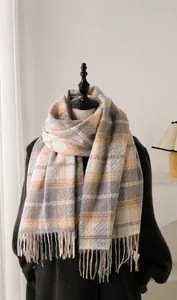 Detail of 100% imitation cashmere scarf featuring orange plaid pattern and fringe