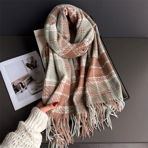 Détail d'une écharpe d'hiver à carreaux doux avec franges en orange et vert