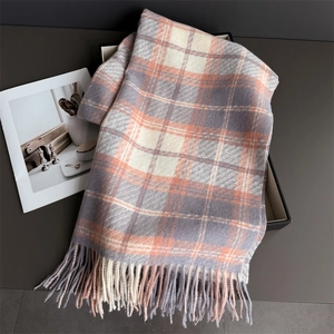 Gros plan d'une écharpe à carreaux orange et gris avec de longues franges et texture douce