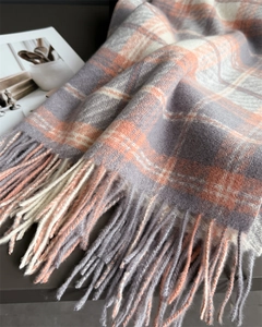 Détail d'une écharpe à carreaux douce avec franges, motifs gris et orange mélangés