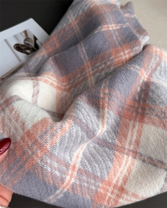 Gros plan sur l'écharpe à carreaux rose saumon et gris avec texture cachemire