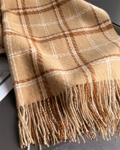 Gros plan sur l'écharpe à carreaux camel montrant la texture douce et les franges