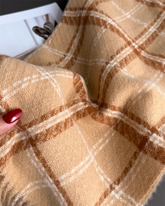 Gros plan d'une écharpe à carreaux et glands doux avec une texture en cachemire de luxe