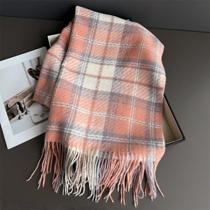Vue détaillée d'une écharpe à carreaux rose et gris avec texture douce et détails à franges