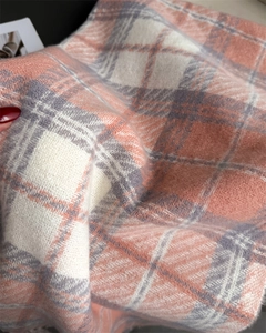 Gros plan détaillé de la texture douce de l'écharpe à carreaux rose blanc et gris