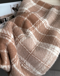 Gros plan sur l'écharpe à carreaux marron et blanc avec une texture douce brossée
