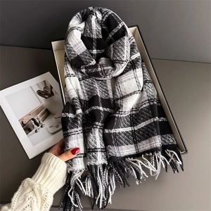 Détail d'une écharpe à carreaux noirs et blancs avec franges dans un coffret cadeau