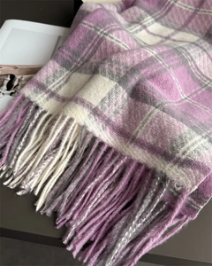 Gros plan d'une écharpe à carreaux violets et gris avec texture douce et détails de franges