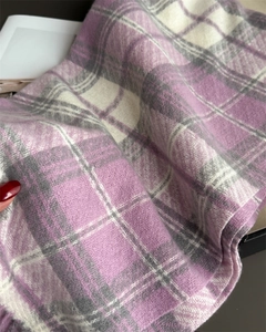 Gros plan sur une écharpe à carreaux violets avec texture brossée et détails à franges