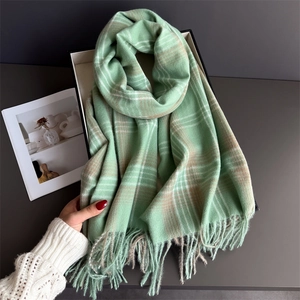 Detailed close-up of light green checkered scarf with soft cashmere-like texture and tassels