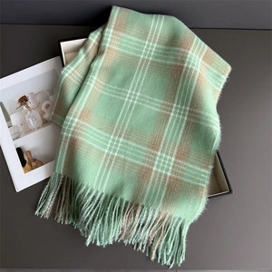 Close-up of mint green and brown checkered scarf with soft texture and knotted tassels