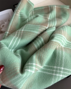 Detailed texture of soft mint green and beige plaid checkerboard faux cashmere scarf