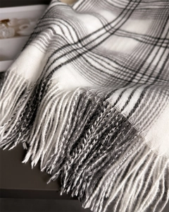 Close-up of classic checkered cashmere-like scarf showing fine tassel fringe detail
