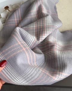 Close-up of soft cashmere-feel fabric texture and grey-pink checkered pattern scarf