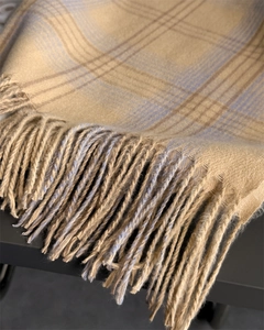 Close-up of soft plaid scarf fringe and texture in beige, blue, and brown tones