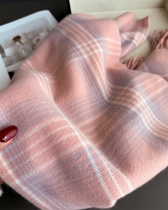 Close-up of soft checkered scarf with fringe detail in pastel pink and white knit
