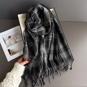 Close-up of black and white checkered scarf with soft fringe and thick warm knit texture