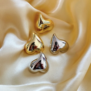 Boucles d'oreilles cœur polies plaquées or 18 carats et argent sur satin champagne