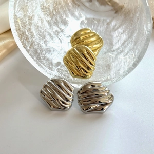 Detailed view of polished gold and silver irregular textured hoop earrings on silk fabric