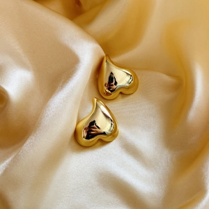 Boucles d'oreilles cœur en plaqué or 18 carats sur un tissu en soie jaune élégant