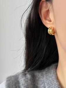 Detail view of bold gold C-shaped chunky hoop earrings with a polished metallic finish
