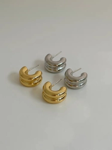 Detail view of double-layered C-shape stud earrings in polished gold and silver finish