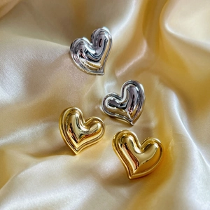 Vue macro des boucles d'oreilles cœur dorées et argentées sur fond en satin élégant