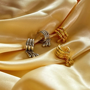 Close-up of gold and silver multi-layer curved drop earrings on champagne silk fabric