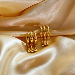 Polished gold multi-layer geometric earrings with triple teardrop charms on satin