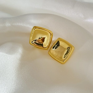 Gros plan de boucles d'oreilles carrées en or poli sur un fond en soie blanche