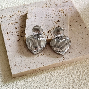Boucles d'oreilles cœur argentées avec texture nervurée sur pierre de travertin
