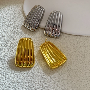 Macro shot of geometric trapezoid earrings with vertical striped texture in gold and silver