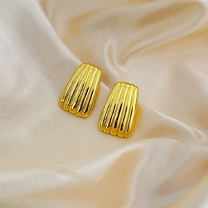 Golden trapezoid earrings with vertical ribbed texture on champagne satin background