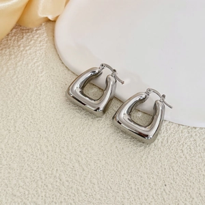 Polished silver chunky square hoop earrings with lever back closure on beige background