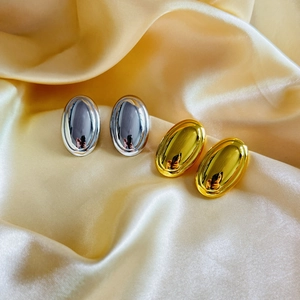 Macro detail of high-polish oval geometric earrings in gold and silver finish