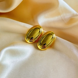 Polished 18K gold plated oval earrings with minimalist geometric design on silk background