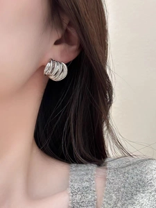 Gros plan de boucles d'oreilles cercles argentés superposés portées par un mannequin