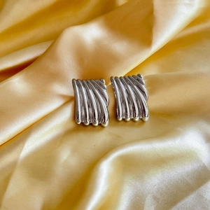 Polished silver geometric rectangular earrings with vertical wavy ridges on gold satin