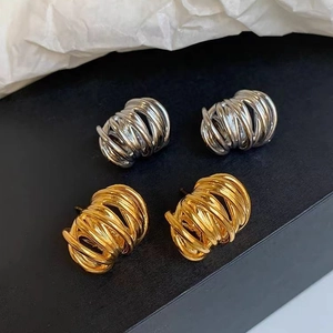 Boucles d'oreilles géométriques torsadées en or et argent sur un fond minimaliste chic