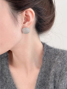 Close-up of silver dome earrings with fine textured metallic bead surface on a model
