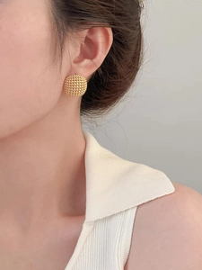 Close-up of a model wearing a gold geometric round beaded texture hollow stud earring