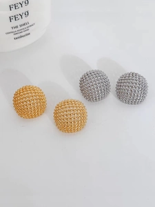 Detailed macro of hollow mesh spherical stud earrings in gold and silver finishes