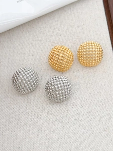 Detailed view of spherical stud earrings with textured gold and silver metal beads