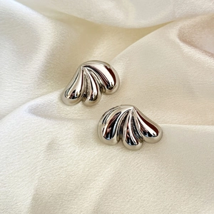 Polished silver tiered drop earrings with wavy scallop texture on beige silk fabric