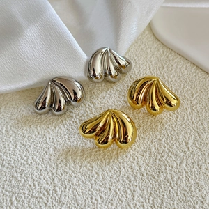 Macro detail of triple-layered teardrop earrings with gold and silver pleated textures